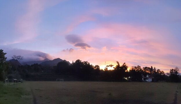 The beauty of sunrise on a field with mountains and clouds in the background