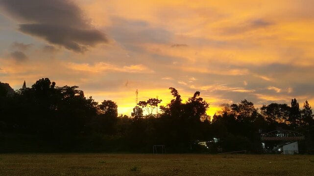 The beauty of sunrise on a field with mountains and clouds in the background