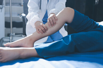 Fototapeta premium Female doctor hands doing physical therapy By extending the leg and knee of a male patient