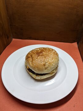Mini burger on a white plate, with a wood and orange background
