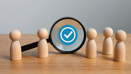 Wooden figures under magnifying glass with checkmark