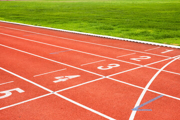 Red running track with numbered starting lines outdoor for organizing sports competitions and exercising for health.