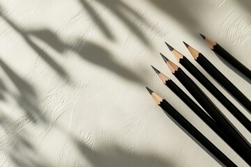 Black Pencils on Textured Surface with Shadows and Natural Light