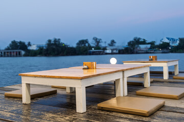 A wooden table with a white tablecloth and a few chairs with cushions