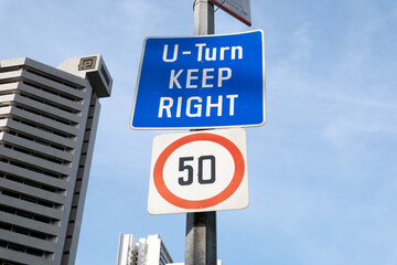 U-Turn road sign with speed limit in Orchard Road, Singapore skyline