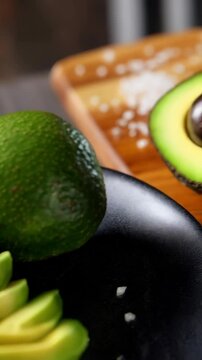Close-up of sliced, whole, and halved fresh avocados, showcasing smooth texture and vibrant green color, food photography