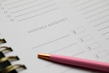 monthly expenses on a notebook with a bright pink pen