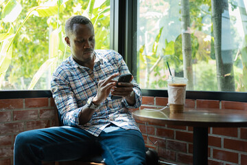 Man Relaxing in Cafe, Browse Smartphone, African Man Enjoying Coffee and Mobile Phone, Casual Business or Leisure with Technology at Cafe