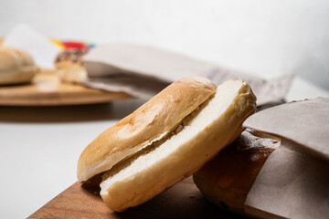 Closeup view of slice of bagel breads from brown paper bag on wooden board on a white background