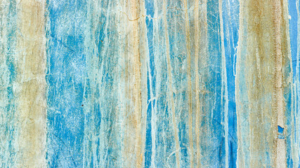 The rough texture of the blue concrete wall has white and brown crusts due to exposure to salt water.