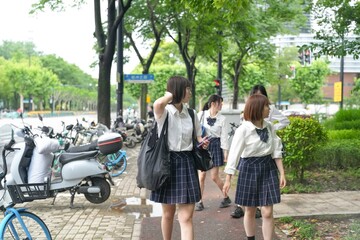 In early June in Pudong, Shanghai, seven Japanese high school girls in summer uniforms walk...