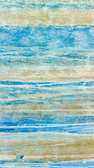 The rough texture of the blue concrete wall has white and brown crusts due to exposure to salt water.