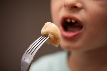 A closeup of a young child eating a plemeni on a fork