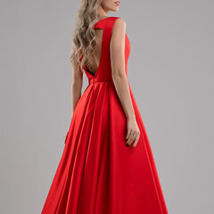 Elegant woman showcasing a red dress in a minimalist studio setting