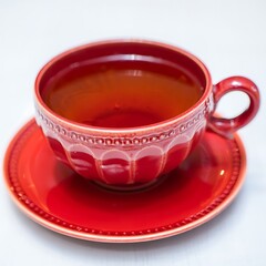 Red teacup filled with tea on saucer