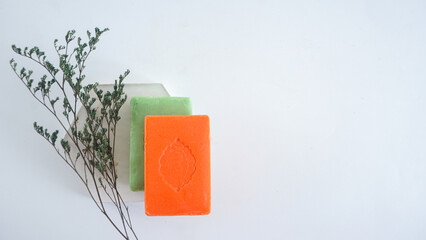 Top view of handmade bar soaps on hexagonal coaster with dried plant isolated on white background