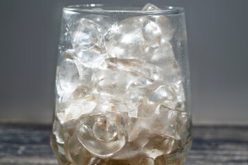 Transparent glass with ice cubes on the table. Drink and refreshment concept