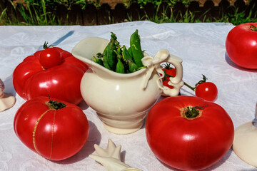 huge tomatoes, cherry tomatoes and green peas as spring table decoration in the garden.