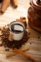 Cafe de Olla. Traditional Mexican coffee and basic ingredients for its preparation, coffee, cinnamon and piloncillo, served in a metallic cup called "peltre" on a rustic wooden surface.