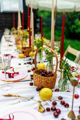 holiday concept - romantic table setting with white tablecloth, plates, crystal glasses, cherries.