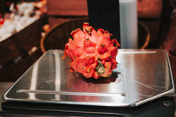 Red pitahaya on the scales in a supermarket. Weighing fruits before buying. Exotic fruits in the store