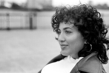 Young woman with curly hair posing outdoors in monochrome analog film photography