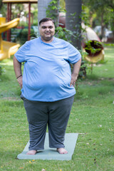 Overweight indian man standing in summer park. Smiling Plus size guy looking camera. Obesity...