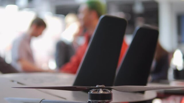 Man in a red shirt is standing behind two black chairs. The chairs are facing the camera and the man is looking away. The scene is blurry and the chairs are the main focus of the image