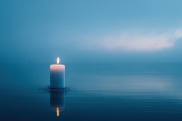 Fototapeta premium A single, lit white candle floats on calm, blue water under a hazy twilight sky, its reflection mirrored below