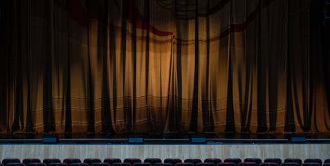 Theater stage with partially open curtain and empty seating, anticipating the show