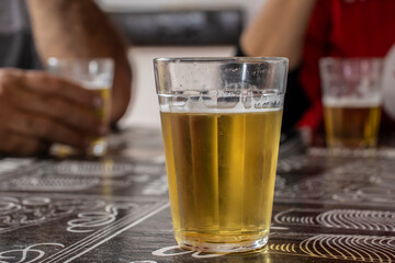 glass full of beer and foam on a bar table in Brazil. Typical Brazilian after-work meal with beer. Selective focus