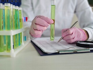 Scientist conducts experiment with test tubes and records data in laboratory
