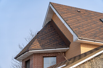 Architecture: Close-up of gable roof with asphalt shingles and brick wall during daytime