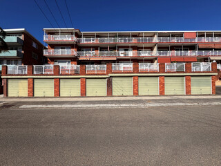 street view of eight green garage doors in a row on old red brick apartment building in Australia