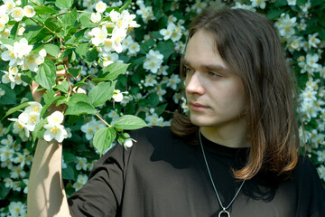 Young man surrounded by blooming flowers in a lush garden setting