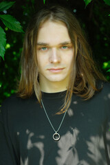 Young person with long hair and striking gaze in nature's embrace