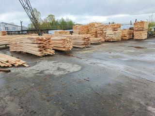 Boards and lumber are stacked in the open air.