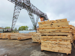 Boards and lumber are stacked in the open air.