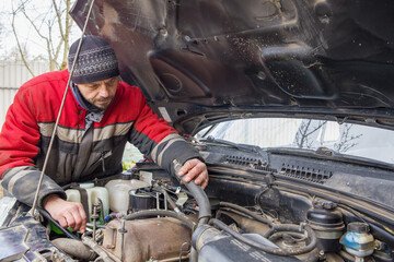 A man, a European, 50 years old, is engaged in car repairs.