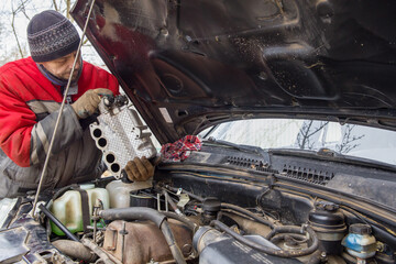 A man, a European, 50 years old, is engaged in car repairs.