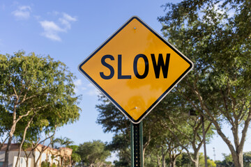 A yellow diamond shaped caution sign with the word Slow written on it