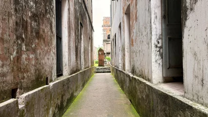 Fototapete Enge Gasse Pathway Between Aged Buildings With Mossy Walls And An Old Mausoleum In Bangladesh  © IT'S ORA CF ID: #078