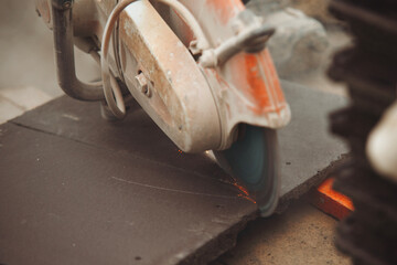 Close-up of roofer cutting roof tiles with petrol power saw on construction site for home...
