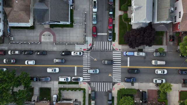 Drone footage of a New York City crossroad showing cars navigating the junction during daytime. A top-down perspective reveals organized traffic patterns in a modern metropolis.