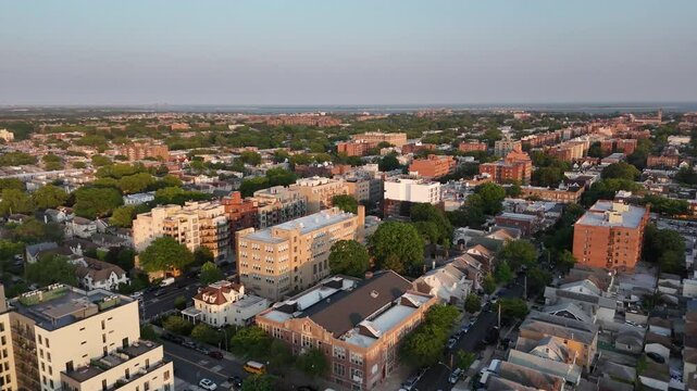 Aerial view over Brooklyn&rsquo;s mixed residential zones, showing tree-lined streets, rows of family homes, and scattered apartment complexes in dense summer foliage and bright urban light.