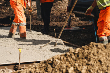 Builder uses spazzle to evenly level freshly mixed concrete on construction site ensuring smooth and durable surface