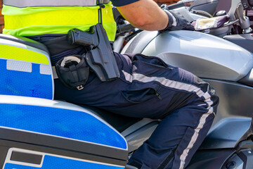 police officer sitting on a service motorcycle. The officer is wearing a high-visibility vest and...