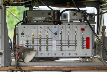Old military radio station from the 1970s–1980s, mounted inside a vehicle. The control panel features numerous switches, indicator lights, and cables, typical of communication equipment used by armed 