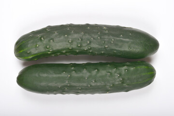 A top-down view displays two dark green cucumbers laid horizontally on a plain white background