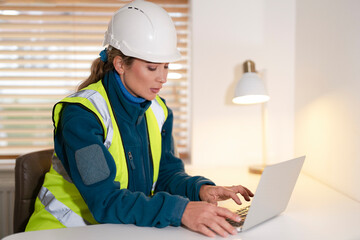 Woman Construction manager reviewing plans and analyzing data while sitting at desk in office